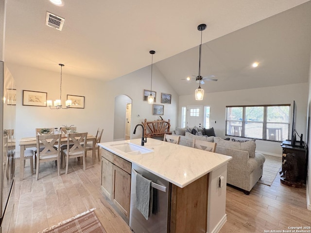 kitchen featuring vaulted ceiling, dishwasher, an island with sink, sink, and light hardwood / wood-style flooring