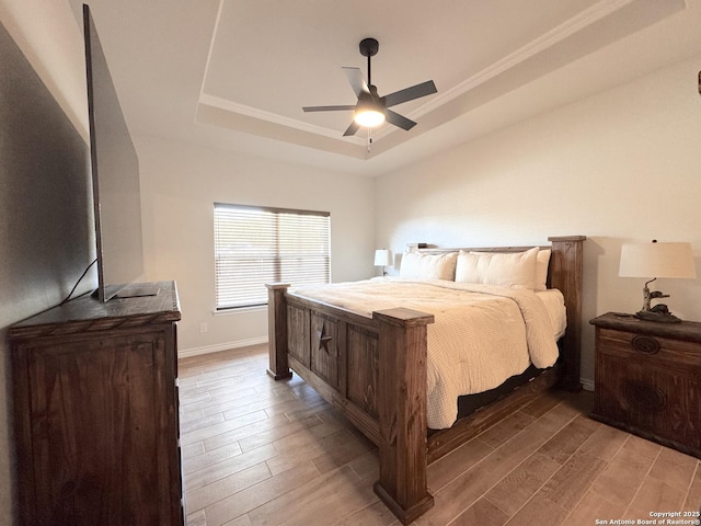 bedroom with crown molding, ceiling fan, a raised ceiling, and hardwood / wood-style floors