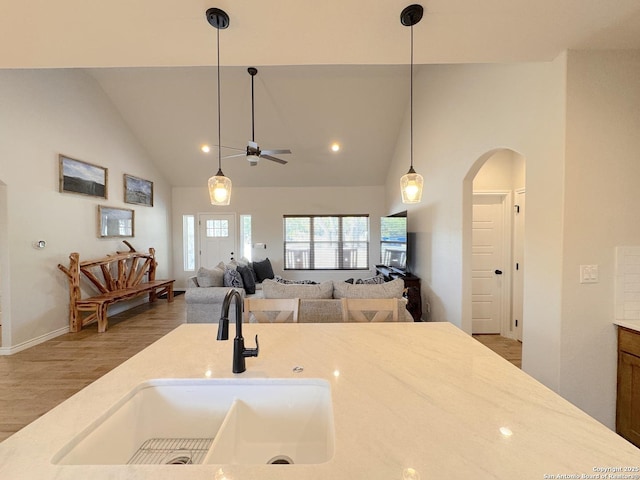 kitchen with high vaulted ceiling, decorative light fixtures, sink, and hardwood / wood-style floors