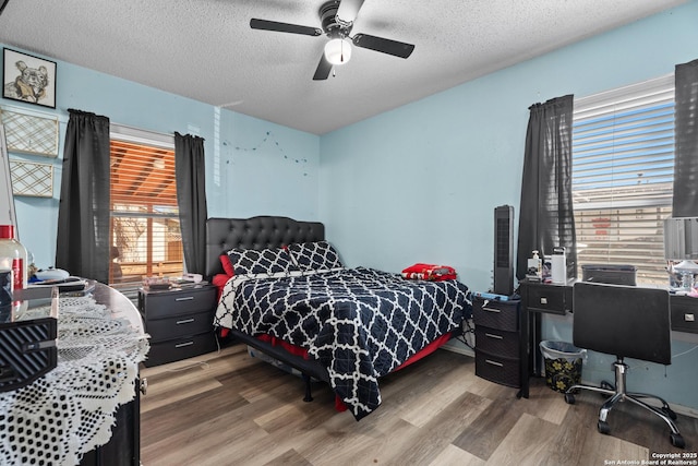 bedroom with a textured ceiling, ceiling fan, and hardwood / wood-style flooring