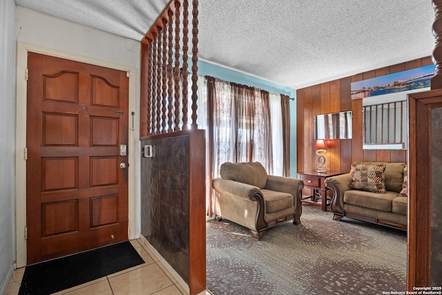 foyer featuring light tile patterned floors, a textured ceiling, and wood walls