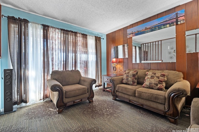 living room featuring carpet floors, a textured ceiling, and wood walls