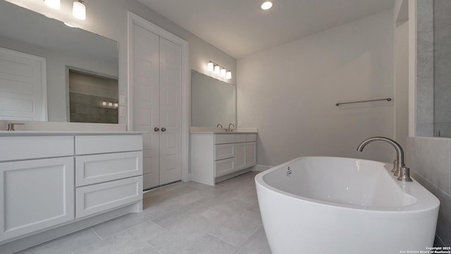 full bathroom with two vanities, a freestanding tub, recessed lighting, tile patterned flooring, and tiled shower