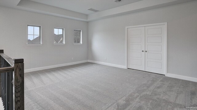 unfurnished bedroom with carpet, baseboards, and a tray ceiling