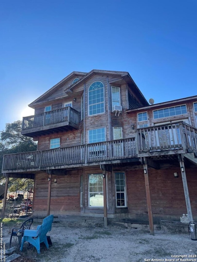 rear view of house with cooling unit and a balcony