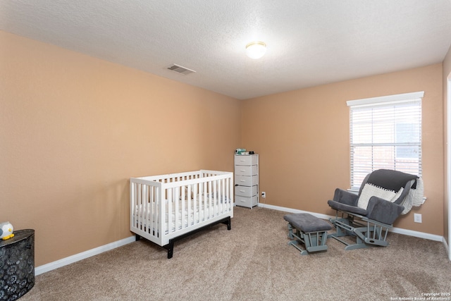 bedroom featuring a crib, carpet flooring, and a textured ceiling