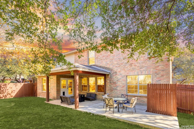 back house at dusk with a yard, a patio area, and french doors