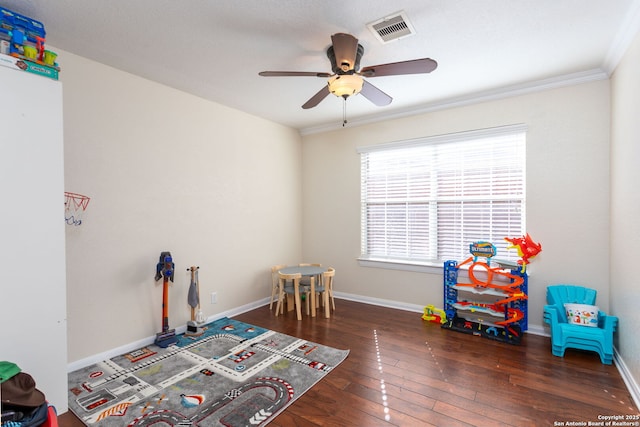 rec room featuring crown molding, dark wood-type flooring, and ceiling fan