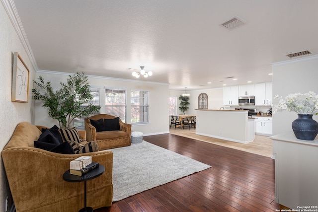 living room featuring an inviting chandelier, crown molding, and dark wood-type flooring