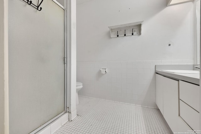 bathroom with tile walls, vanity, an enclosed shower, toilet, and tile patterned floors