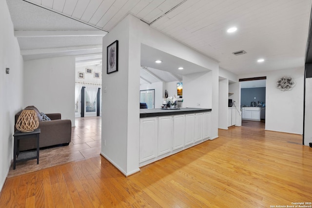 hall with light wood-type flooring and vaulted ceiling with beams