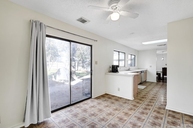 kitchen with dishwasher, sink, ceiling fan, kitchen peninsula, and a textured ceiling