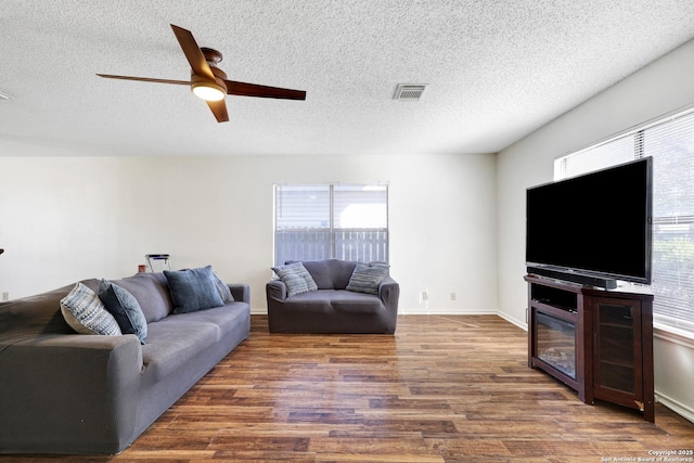 living room with dark wood-type flooring, plenty of natural light, and a textured ceiling