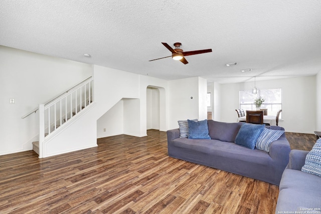 living room featuring ceiling fan, dark hardwood / wood-style flooring, and a textured ceiling