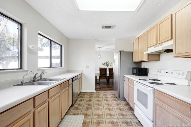 kitchen featuring appliances with stainless steel finishes, sink, light brown cabinets, and a textured ceiling