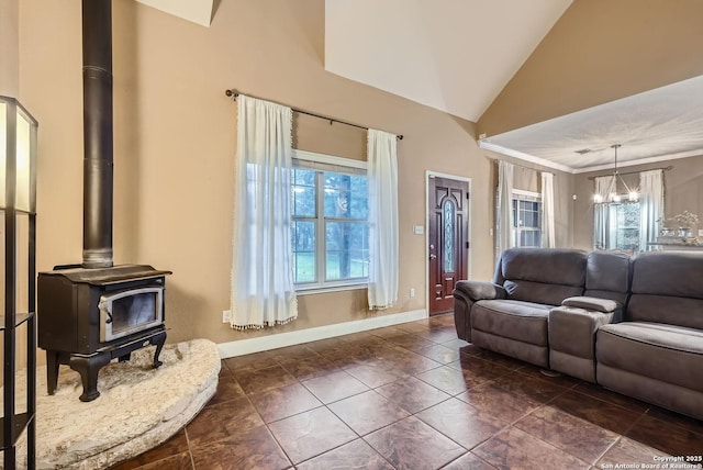 living room with plenty of natural light, a chandelier, high vaulted ceiling, and a wood stove