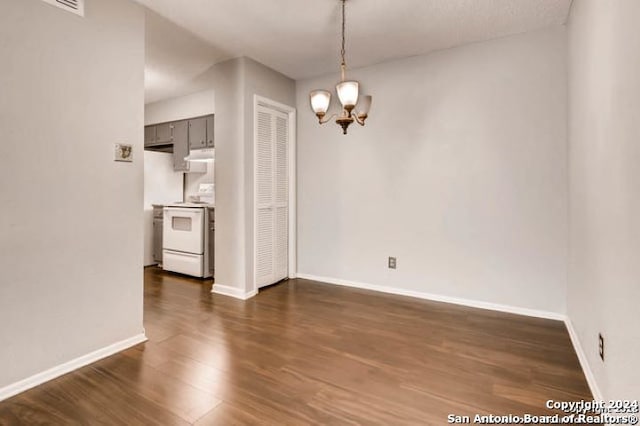 empty room with dark wood-type flooring and a notable chandelier