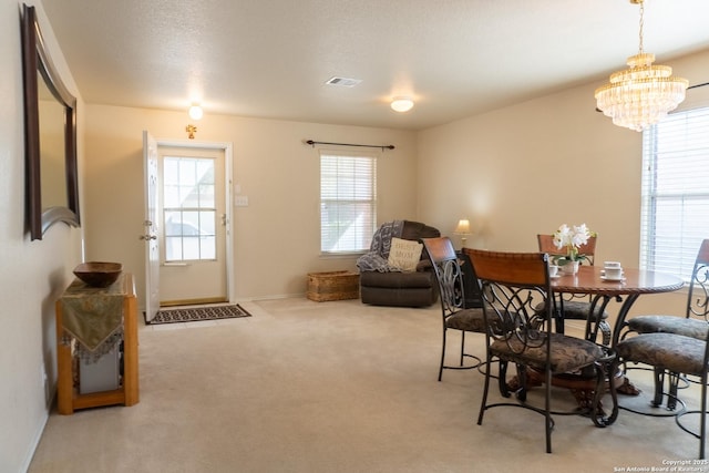 dining area with light colored carpet, a textured ceiling, and an inviting chandelier