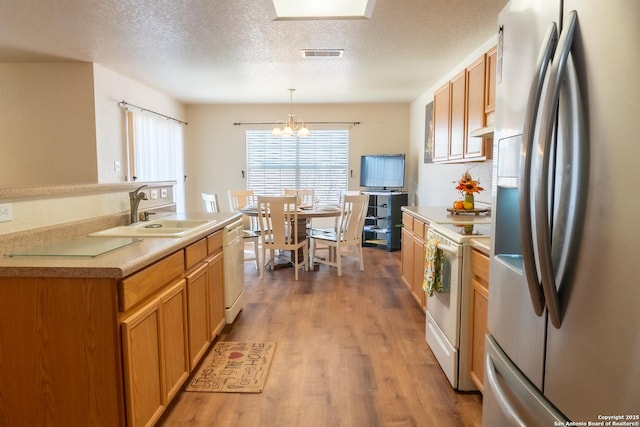 kitchen featuring sink, wood-type flooring, a textured ceiling, pendant lighting, and white appliances