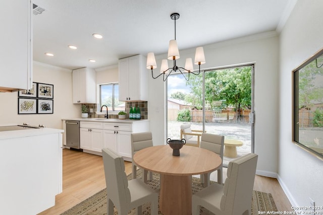 dining area featuring a notable chandelier, ornamental molding, sink, and light wood-type flooring