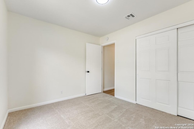 unfurnished bedroom with light carpet and a closet