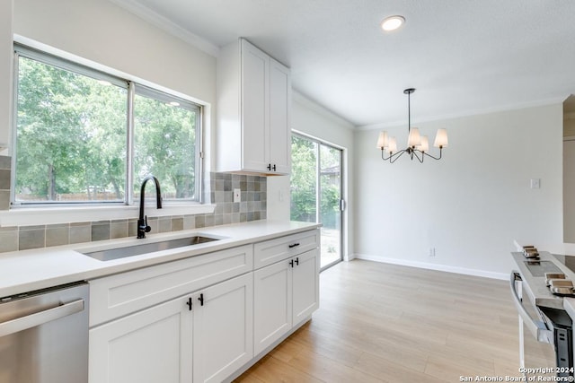 kitchen with decorative light fixtures, dishwasher, sink, white cabinets, and decorative backsplash