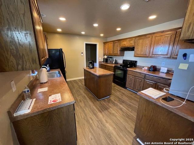 kitchen featuring wood-type flooring, a center island, sink, and black appliances