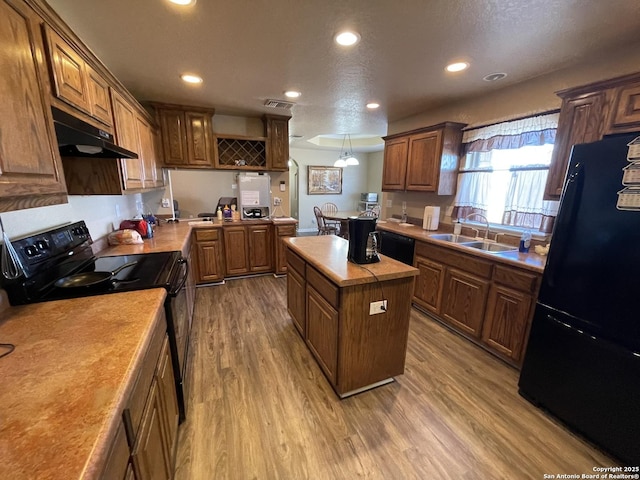 kitchen featuring a kitchen island, sink, hardwood / wood-style floors, and black appliances