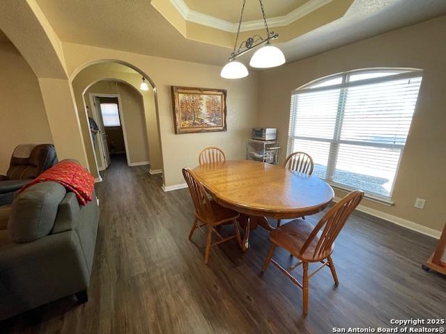 dining space featuring crown molding, dark hardwood / wood-style flooring, and a tray ceiling