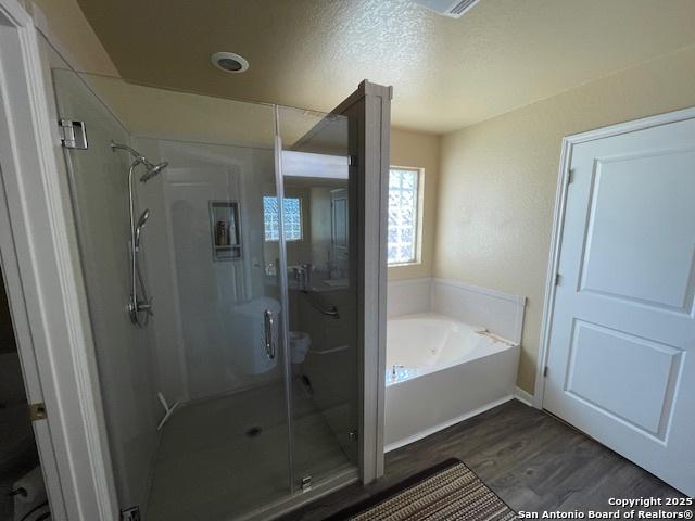 bathroom featuring hardwood / wood-style flooring, shower with separate bathtub, and a textured ceiling