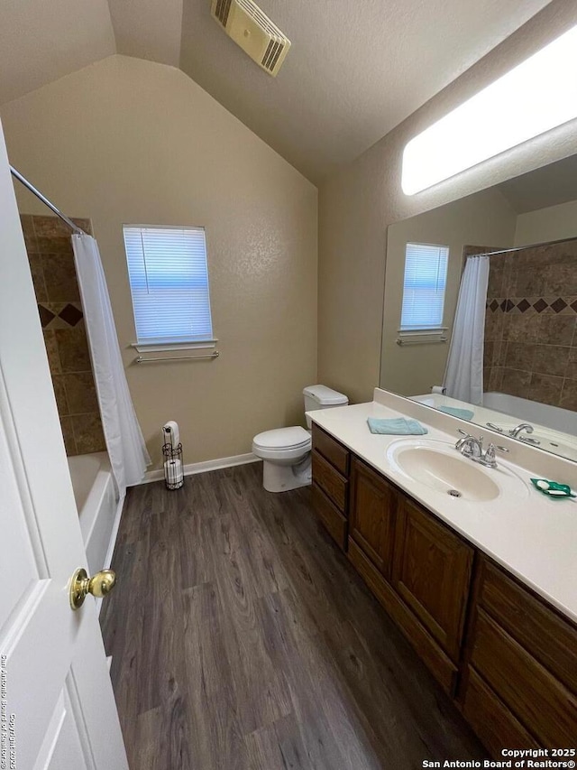 full bathroom featuring vaulted ceiling, hardwood / wood-style flooring, vanity, toilet, and shower / bath combo