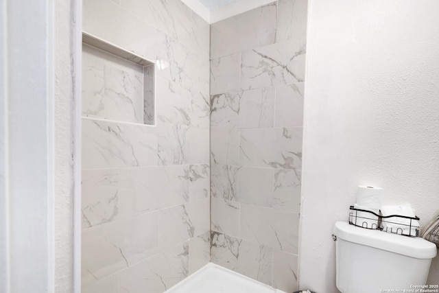 bathroom with tiled shower and toilet