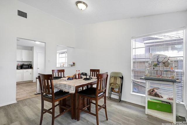 dining area featuring vaulted ceiling and light hardwood / wood-style floors