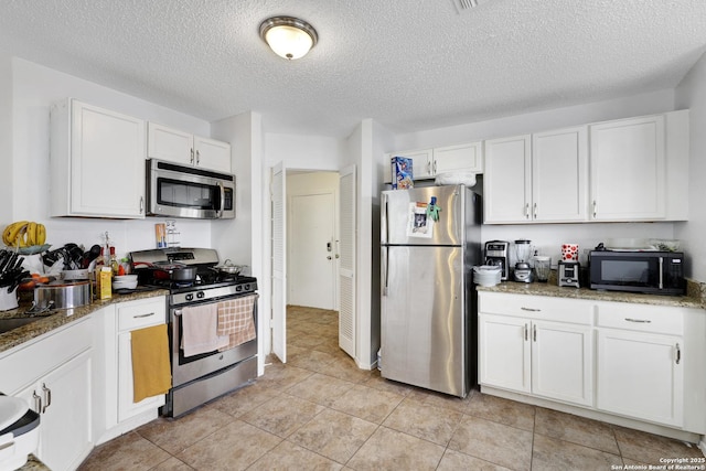 kitchen featuring dark stone countertops, stainless steel appliances, a textured ceiling, and white cabinets