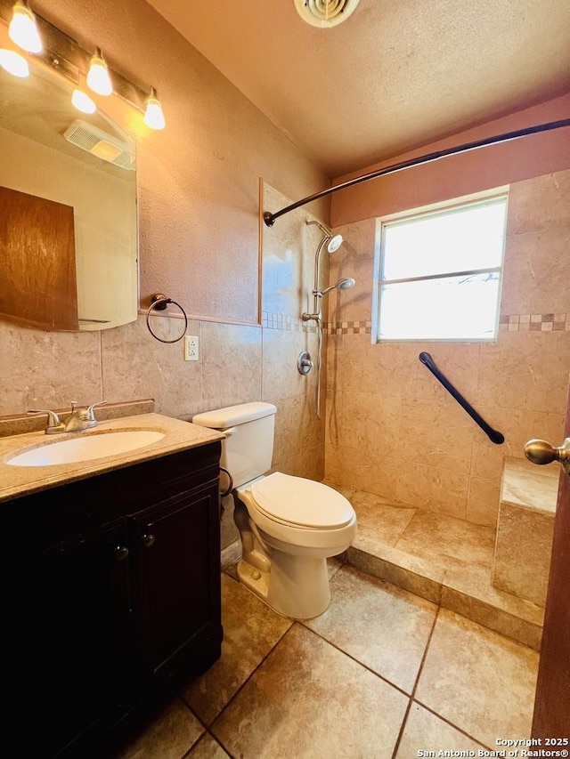 bathroom with tiled shower, tile patterned floors, toilet, tasteful backsplash, and vanity