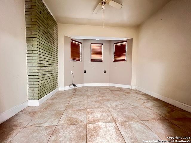 tiled spare room featuring ceiling fan