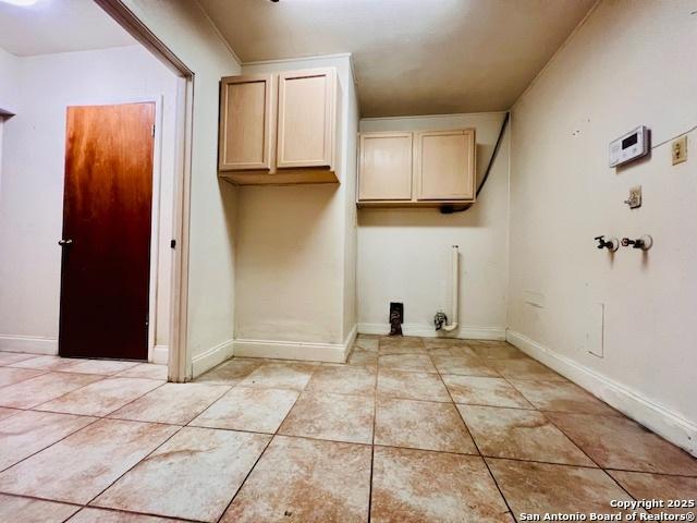 washroom featuring light tile patterned floors, hookup for a washing machine, and cabinets