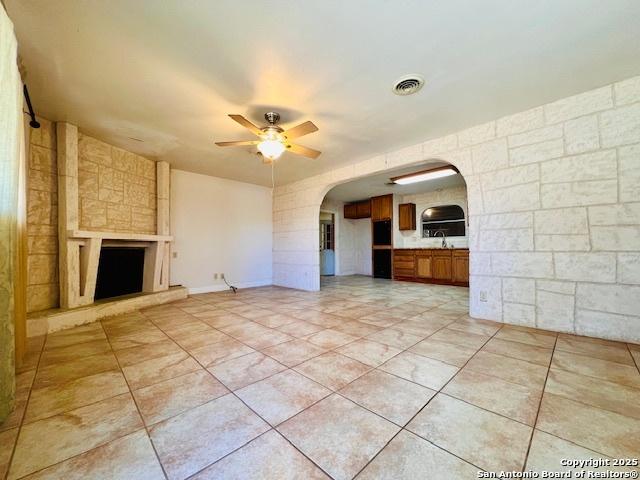 unfurnished living room with a fireplace and ceiling fan