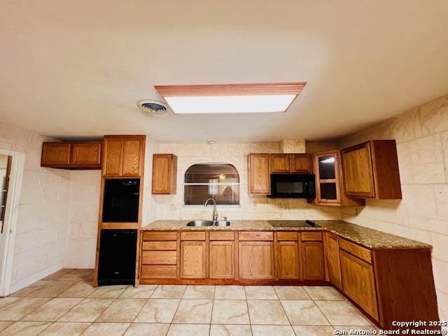 kitchen with light stone countertops, sink, and black appliances