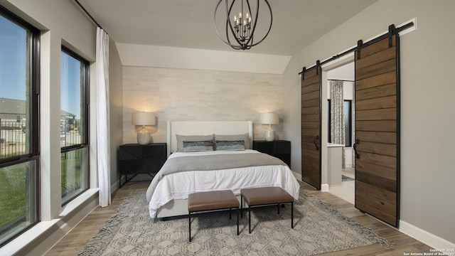 bedroom with multiple windows, a barn door, and light hardwood / wood-style flooring