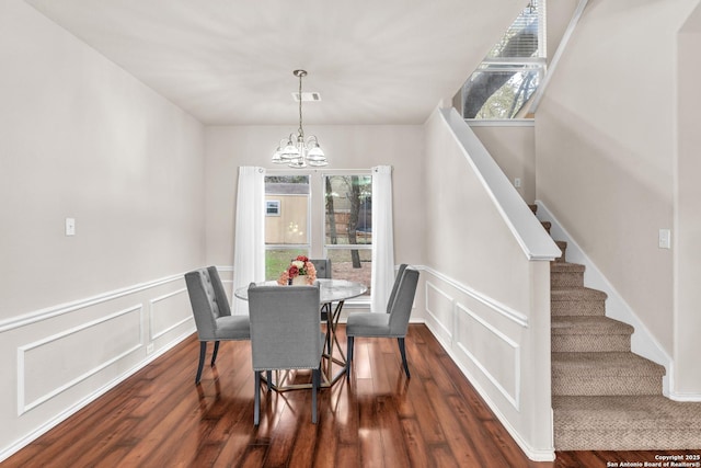 dining room with dark hardwood / wood-style floors and an inviting chandelier