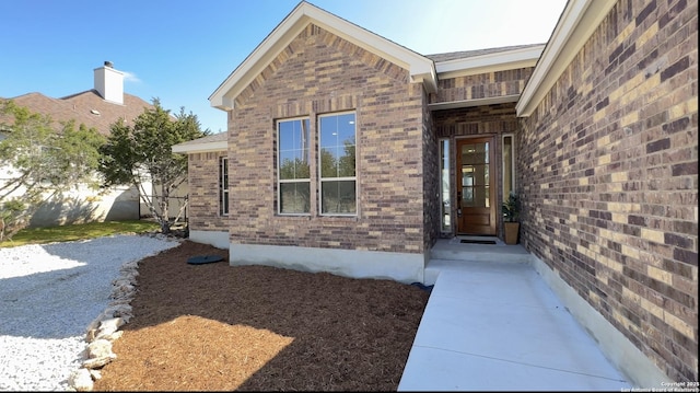 doorway to property featuring fence and brick siding