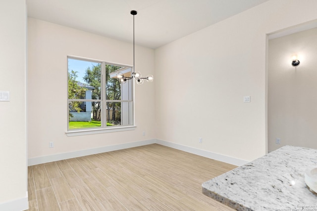 unfurnished dining area with an inviting chandelier and hardwood / wood-style floors