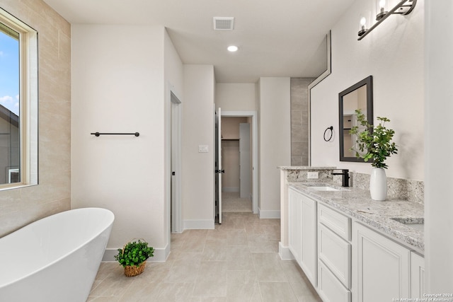 bathroom featuring tile patterned floors, vanity, and a bath