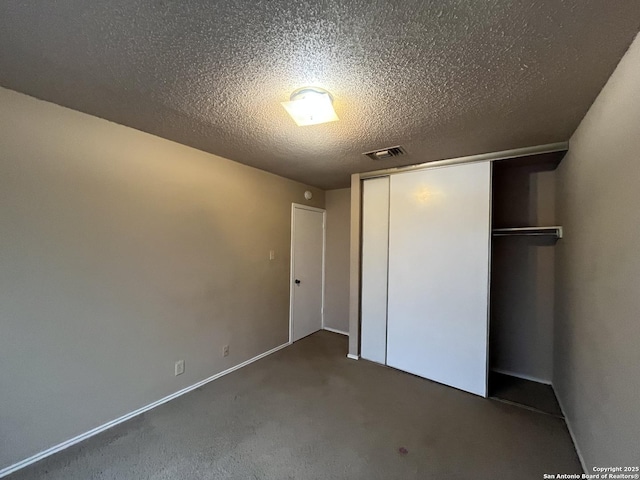 unfurnished bedroom with dark carpet, a textured ceiling, and a closet