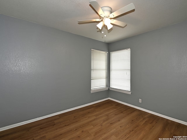 empty room with dark wood-type flooring and ceiling fan