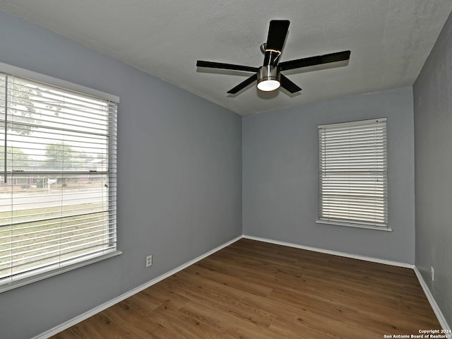 unfurnished room with a textured ceiling, a wealth of natural light, dark hardwood / wood-style floors, and ceiling fan