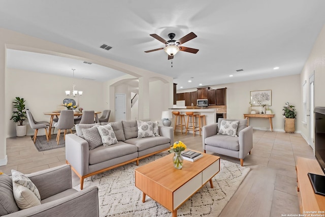 living room featuring ceiling fan with notable chandelier and light wood-type flooring