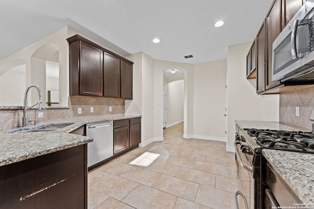 kitchen featuring light tile patterned flooring, appliances with stainless steel finishes, sink, and light stone counters