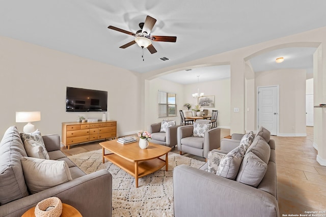 living room featuring ceiling fan with notable chandelier